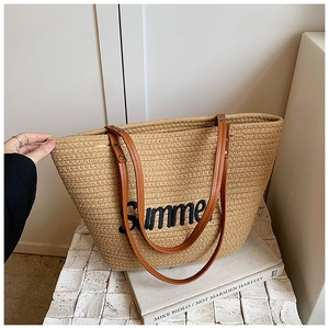 Detail of Summer embroidery on beige woven straw tote bag with brown leather handles