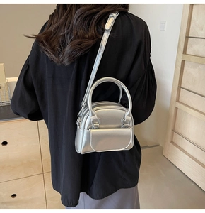 Mini borsa a tracolla argento metallizzato indossata da modella in interno in legno