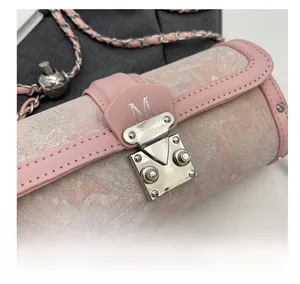 Detail of silver clasp and pink toile de jouy pattern on cylinder chain bag