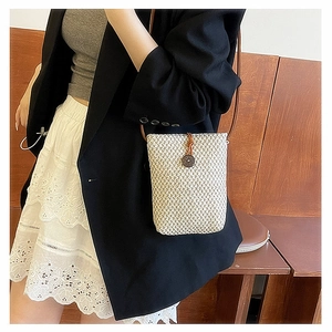 Straw woven crossbody phone bag with retro button detail on female model's side