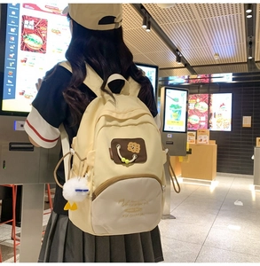 Detail of cream and coffee school backpack with cute biscuit patch and plush duck charm