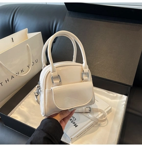Dettaglio mini borsa bowling crema con manici all'interno di una scatola regalo