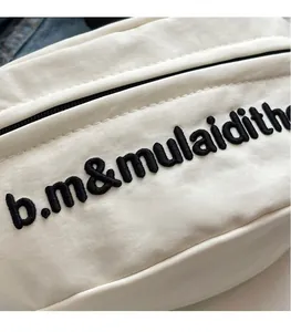 Detail of off-white canvas bag showing black embroidered letters and fabric texture