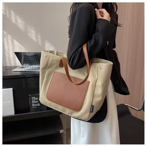 Detail of canvas tote bag with brown leather pocket and metal rivets for office use