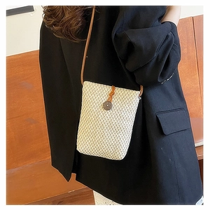 Detailed close-up of woven straw texture and leather strap on a small crossbody bag