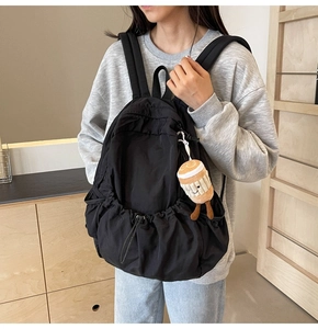Close-up of black nylon backpack with drawstring pocket and cute plush pendant