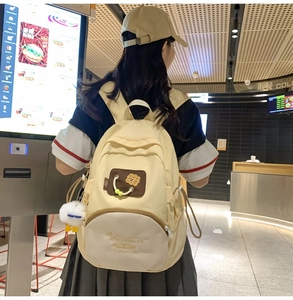 Detail of beige canvas backpack featuring cute cookie patch and refined embroidery work