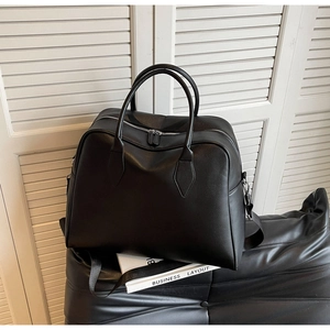 Close-up of black leather tote showing lychee texture and silver double zipper hardware