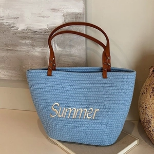 Sky blue woven straw tote bag with brown leather handles and Summer embroidery