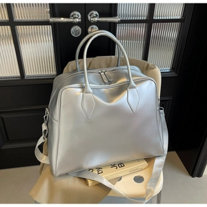 Close-up of metallic silver tote bag featuring reinforced handles and wide textile strap