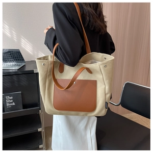 Detail view of canvas tote bag with brown leather pocket and long shoulder straps