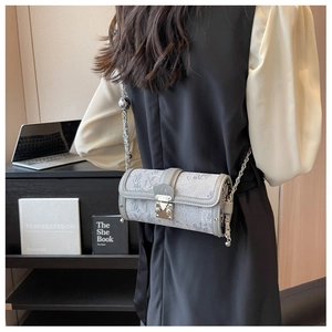 Detail of grey jacquard cylinder bag with silver chain and metal M-shaped clasp