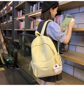 Detail view of yellow backpack featuring a bear patch and pink star plush charm in a bookstore