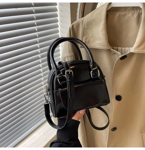 Dettaglio di una mini borsa chic in pelle nera lucida con finiture argento e tracolla