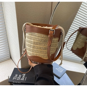 Detail of straw bucket bag featuring brown leather trim and a functional drawstring closure