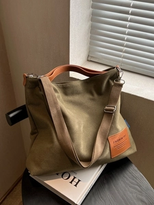 Olive green canvas tote bag with brown leather handles and wide shoulder strap