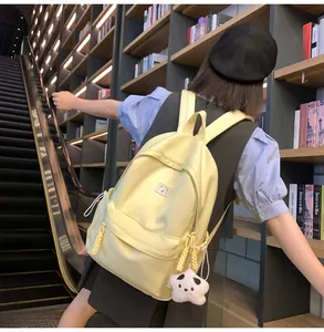 Detail of yellow canvas backpack with panda plush charm in a library setting