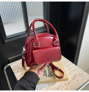 Dettaglio della mini borsa rossa in ecopelle con doppi manici e cerniera metallica argento