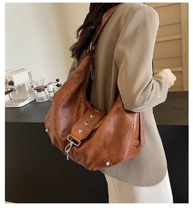 Détail du sac hobo en cuir marron vintage avec rivets étoiles argentées et crochet
