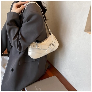 Close-up of minimalist cream crescent underarm bag with silver hardware on a model's shoulder