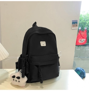 Detail of black nylon backpack with cute bear patch and star plush pendant