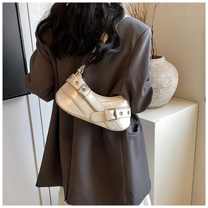 Chic cream crescent shoulder bag featuring stylish metal buckles and eyelet details