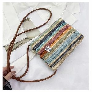 Detail of colorful woven straw crossbody bag featuring floral button and pearl trim accents