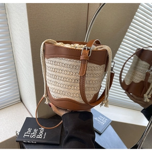 Detailed close-up of straw bucket bag with brown leather trim and drawstring closure