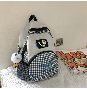 Detail of grey waterproof school backpack with blue plaid pocket and plush doll pendant