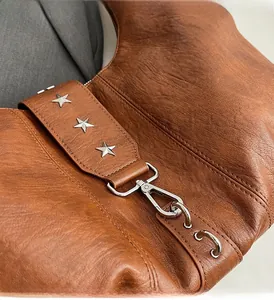 Détail du sac en cuir marron avec rivets en forme d'étoile et ferrures métalliques de qualité
