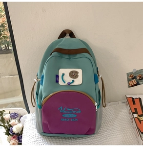 Front detail of stylish color-block nylon backpack with cartoon patch and side mesh pockets