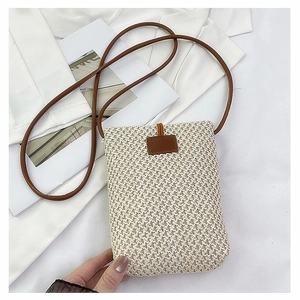 Close-up of woven straw texture and brown leather strap on the compact crossbody phone bag