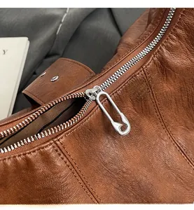 Détail du zip épingle à nourrice argentée sur un sac à bandoulière en cuir marron