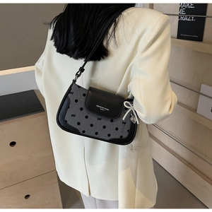 Detail of polka dot underarm bag with pearl bow charm and heart pendant accessory