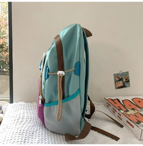 Detail view of the multi-color backpack showing blue and purple nylon with brown side strap