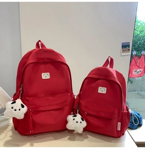 Detail view of large and small red canvas backpacks with bear patches and star charms