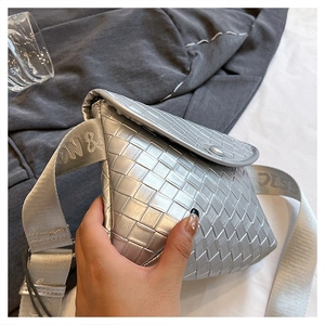 Detalle de la textura tejida plateada y la correa ancha de este bolso de tendencia