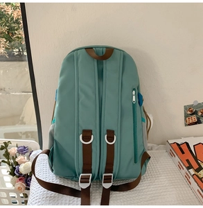 Detail view of mint green canvas backpack featuring brown straps and anti-theft back pocket