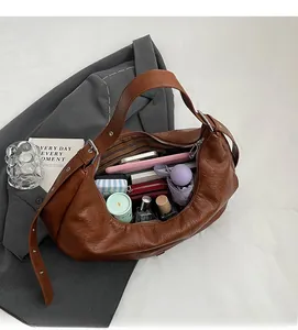 Vue de dessus du sac hobo en cuir marron avec doublure rayée et articles essentiels
