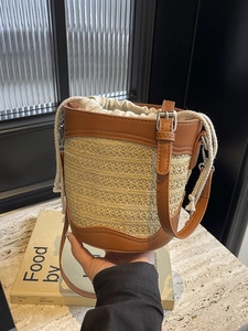 Handcrafted straw bucket bag with brown leather trim and drawstring closure for summer