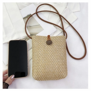 Detailed macro view of woven beige straw texture and dark brown leather strap on mobile pouch