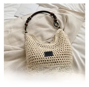 Détail du sac cabas en paille tissée avec poignée en perles de bois marron