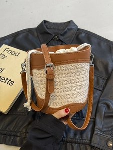 Straw bucket bag with brown leather trim and drawstring for seaside beach holidays