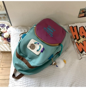 Close-up of multicolor nylon backpack featuring cute biscuit patches and plush pendant