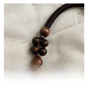 Détail de la sangle tissée main avec perles en bois marron et fermoir en métal doré