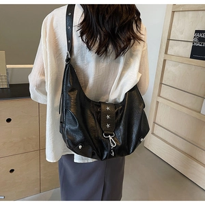 Détail du sac demi-lune noir en cuir avec rivets étoiles argentées et bandoulière large