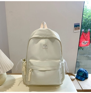 Detail of a minimalist cream white backpack with bear embroidery and woven cord zippers