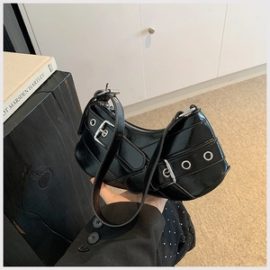 Detail of black patent leather half-moon bag with silver metal rings and buckle