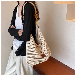 Détail du sac cabas beige tissé avec une bandoulière distinctive en perles de bois