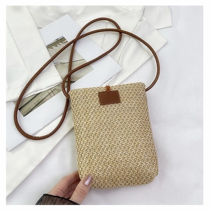 Detail of hand-woven straw small square crossbody bag with brown leather strap